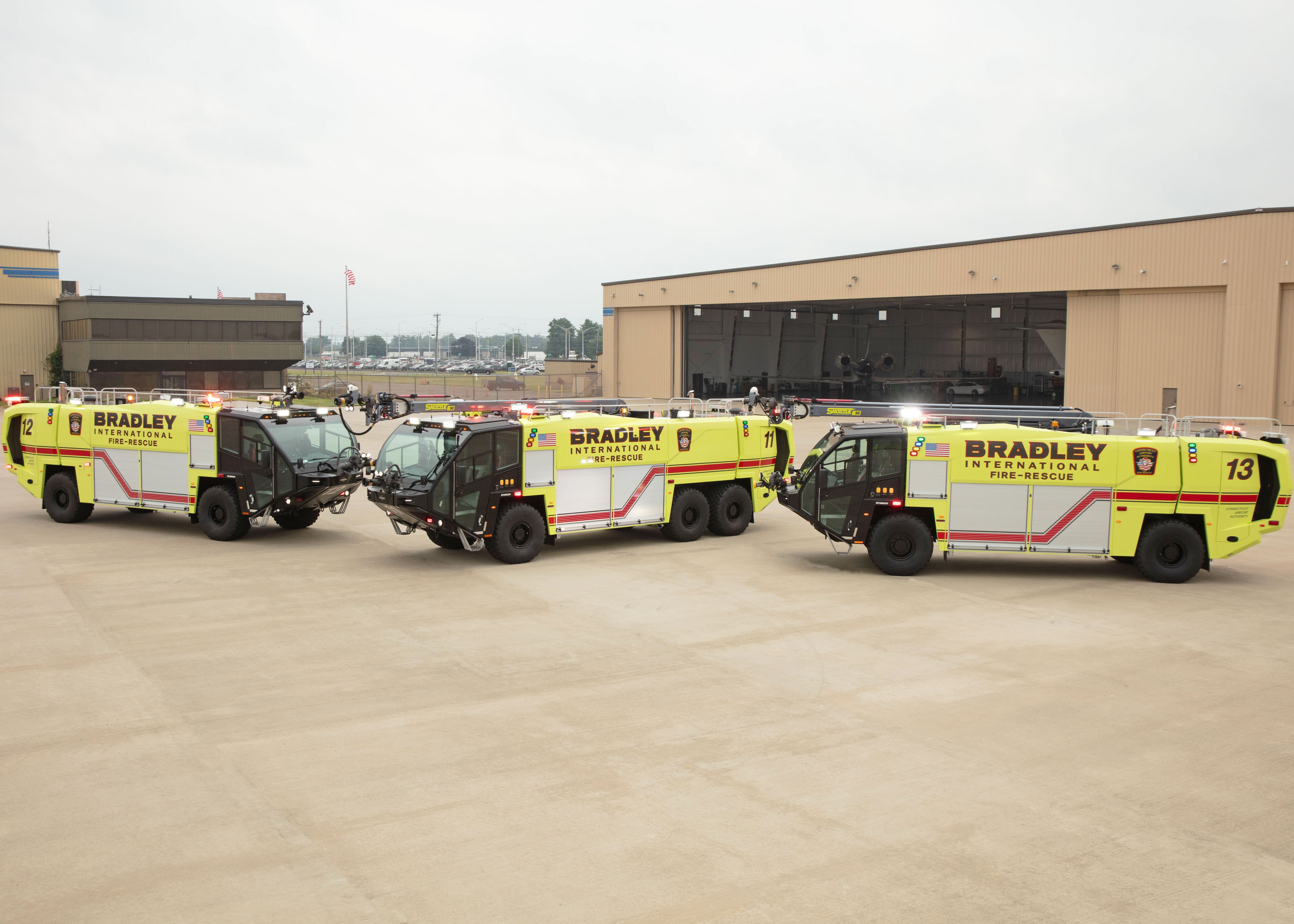 Three Striker ARFF vehicles parked outside on a cloudy day.