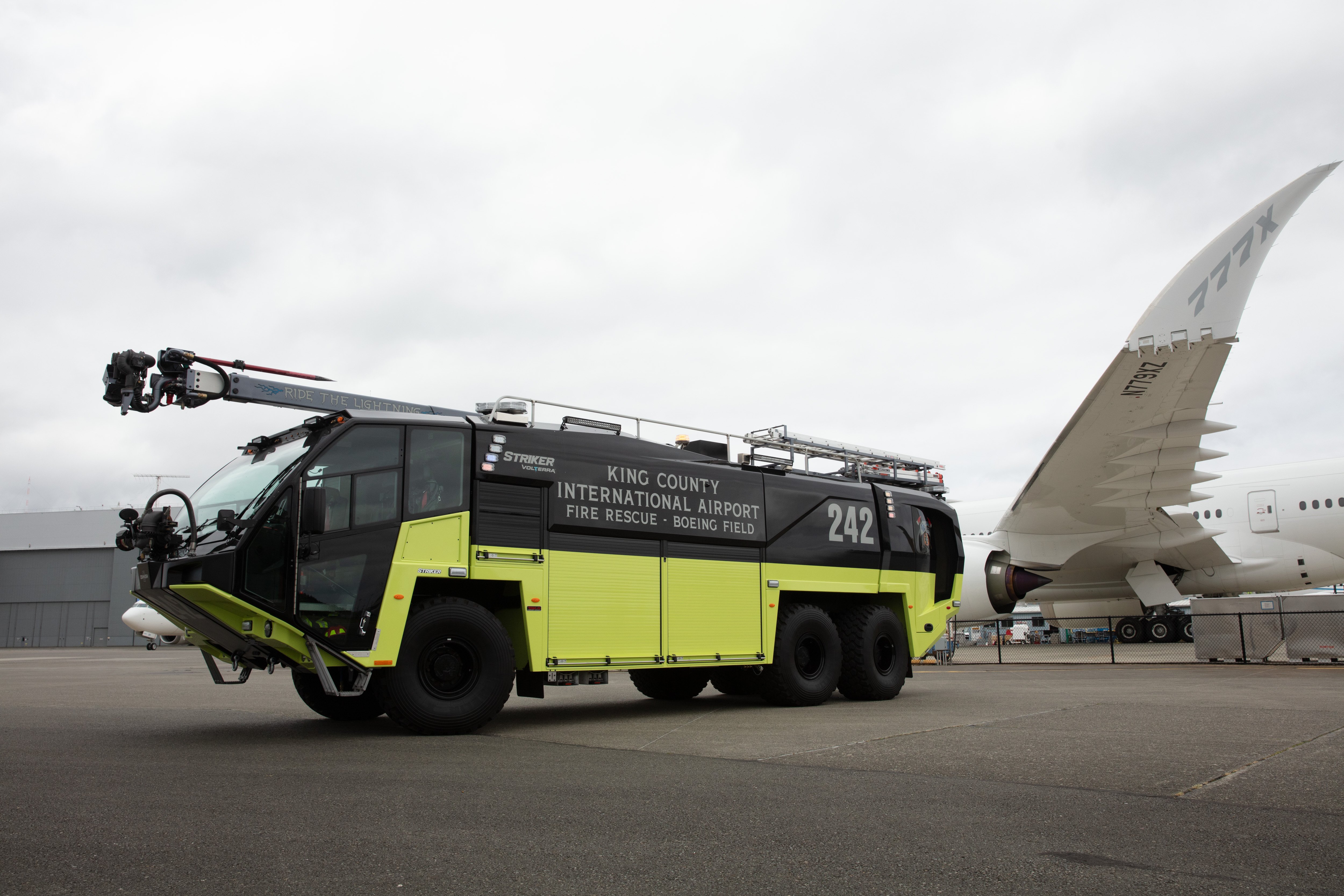 A Striker Volterra Electric ARFF parked outside near the airport on a cloudy day.