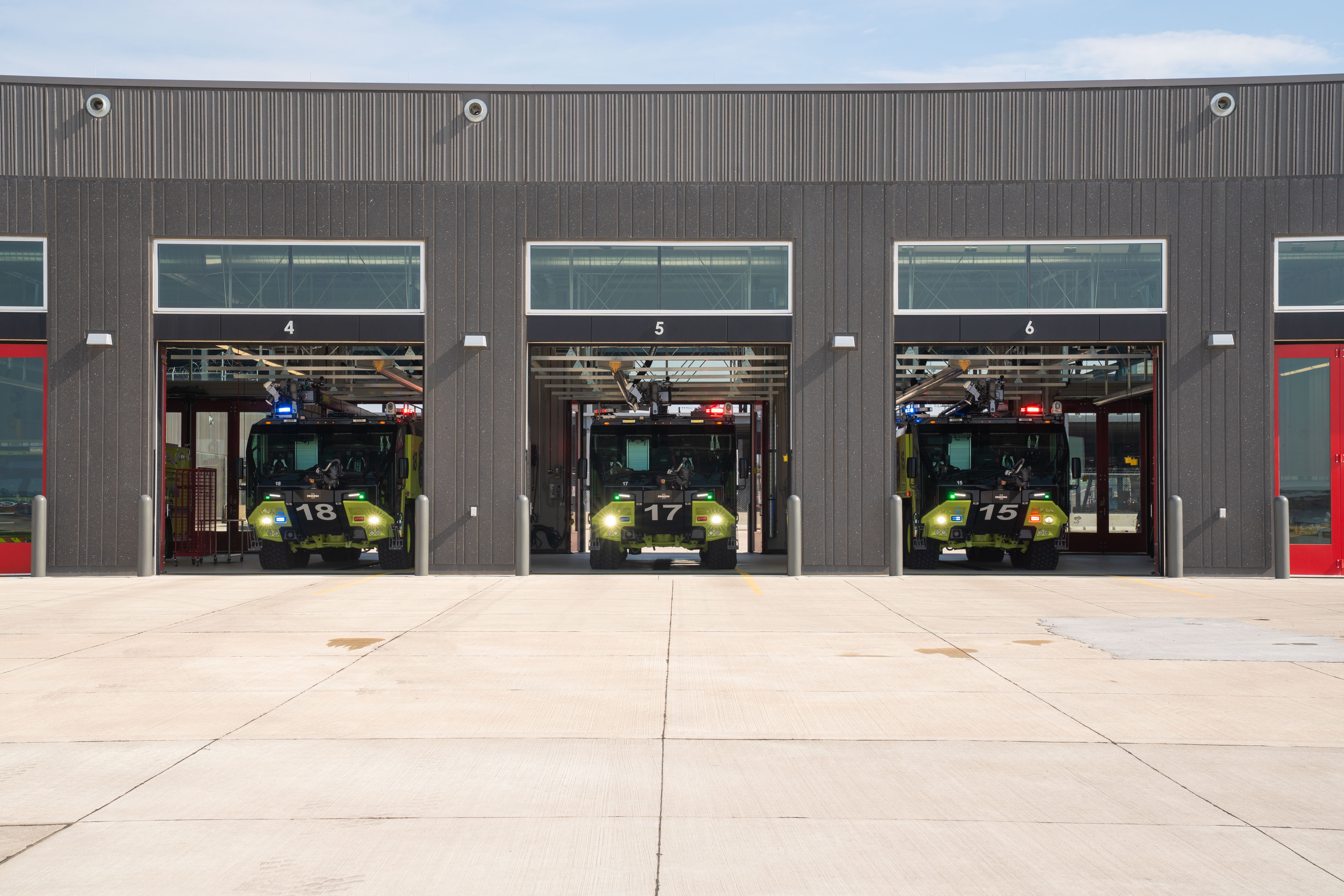 Three Striker 8x8 ARFFs parked inside the fire station on a sunny day.