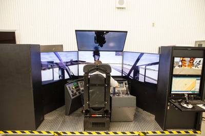 Man operating the Oshkosh Striker ARFF simulator with six total monitors.