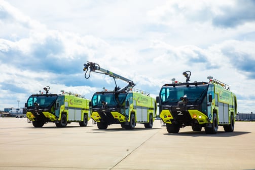 Three Striker 4x4 ARFFs parked outside on a cloudy day.