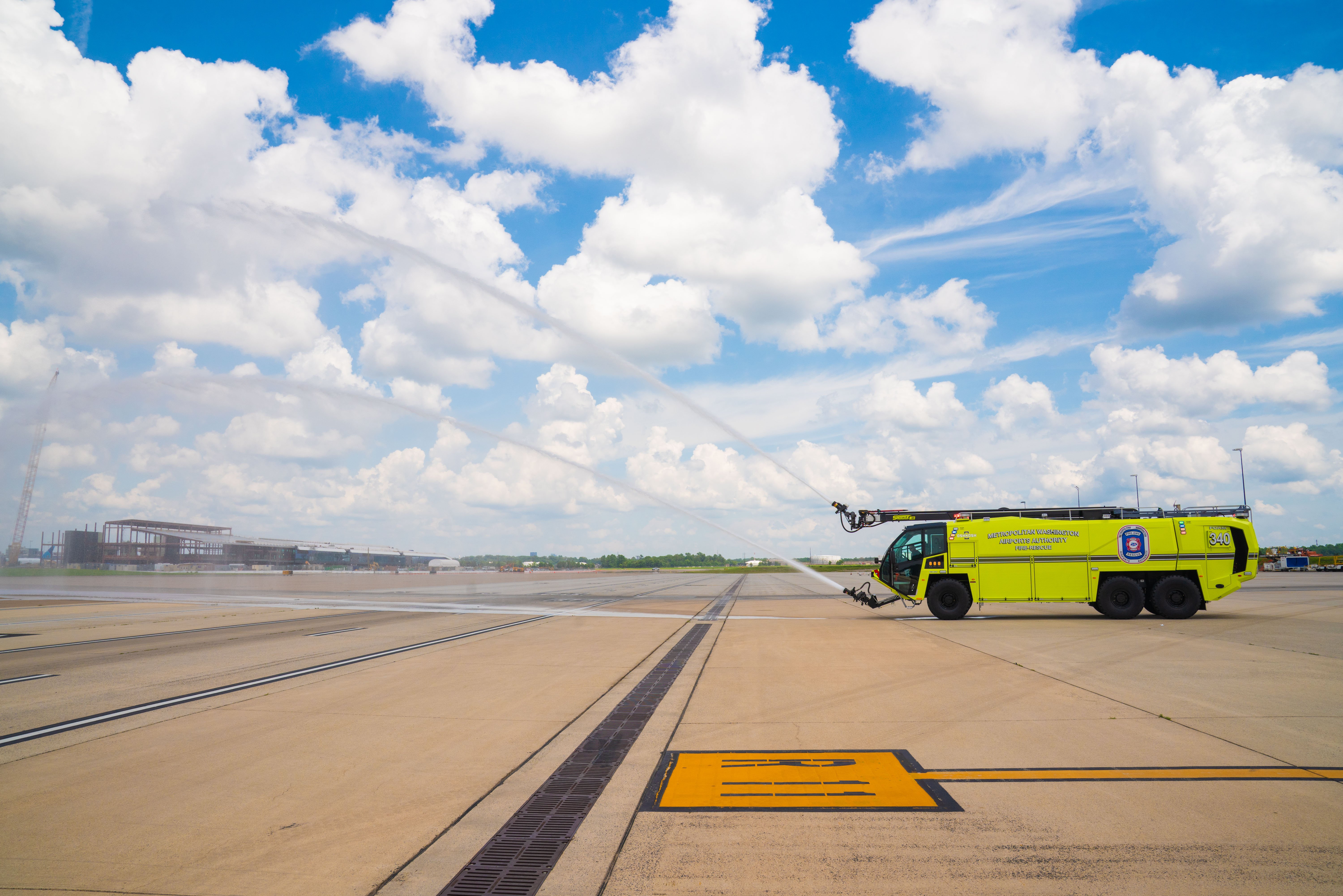 A Striker 6x6 ARFF parked outside on a cloudy day spraying water from the turrets.