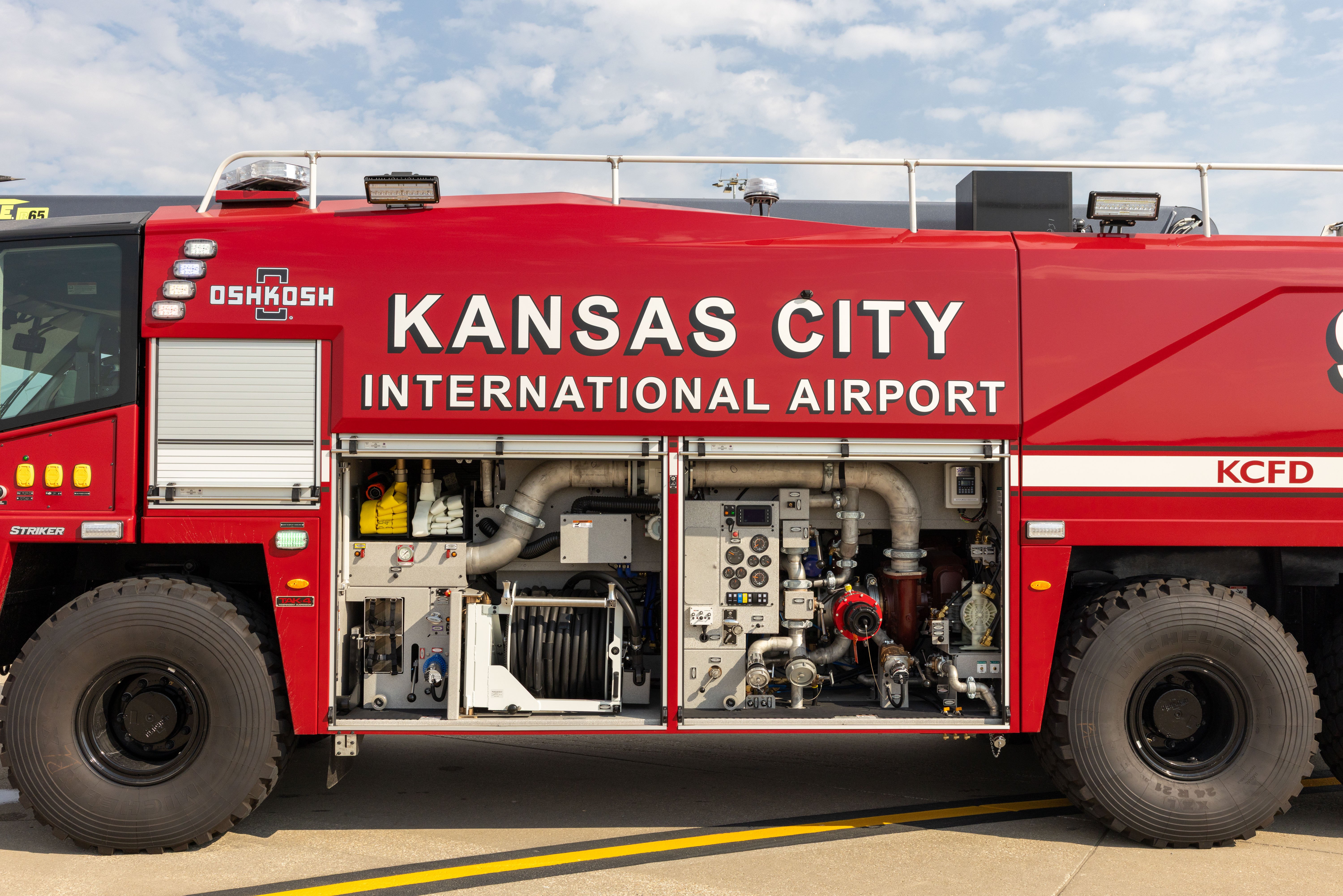 A Striker 6x6 ARFF parked outside on a cloudy day with the compartment doors open. 