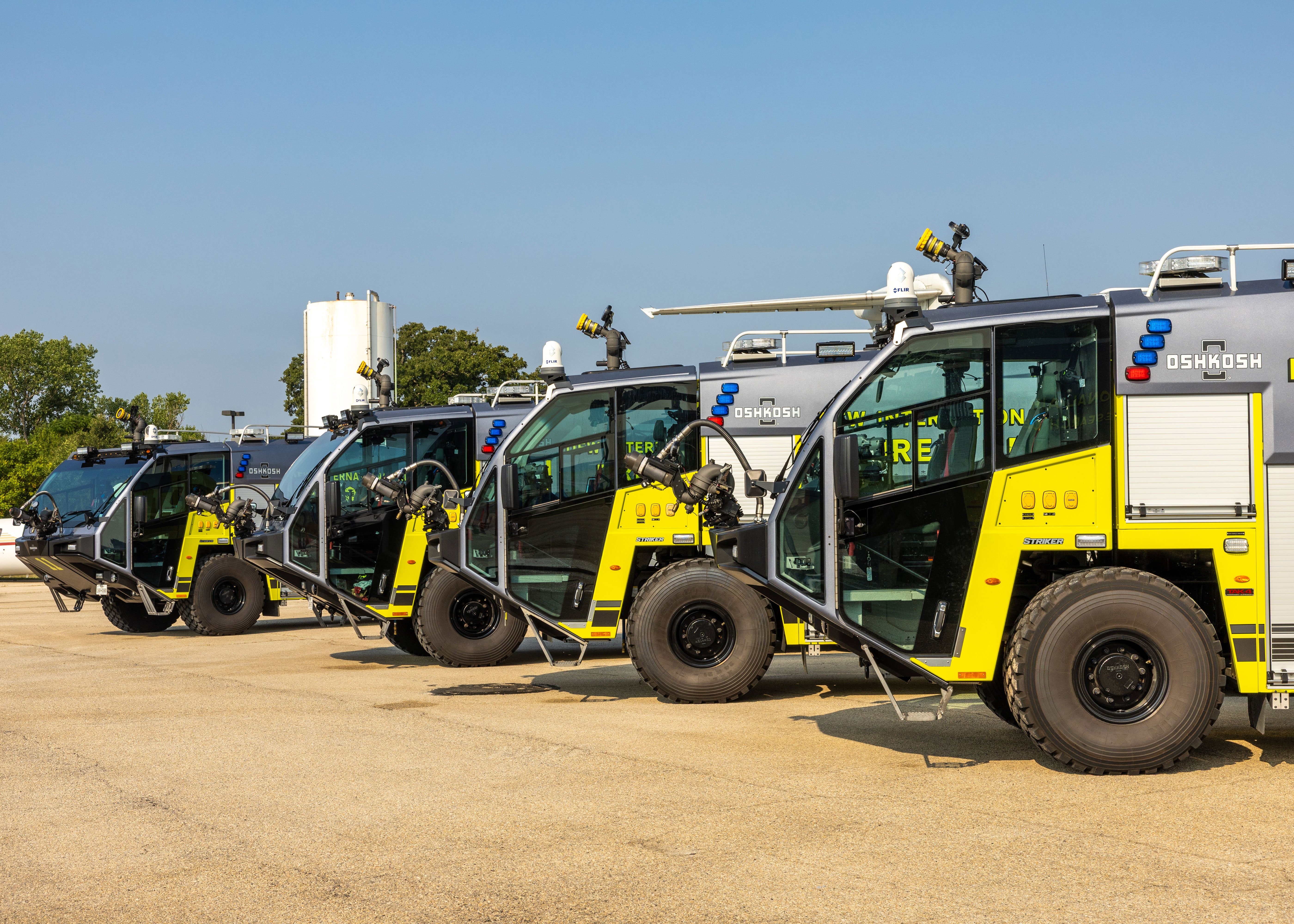 Four Striker ARFF Vehicles parked outside on a sunny day.