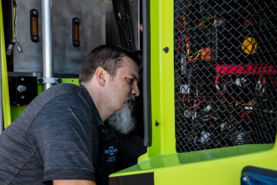 A man in a gray shirt working on the mechanics of a lime green Striker Volterra ARFF