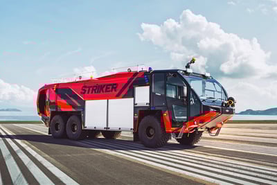 A red ARFF Vehicle with roof turret sitting on pavement with white lines and a blue sky in the background