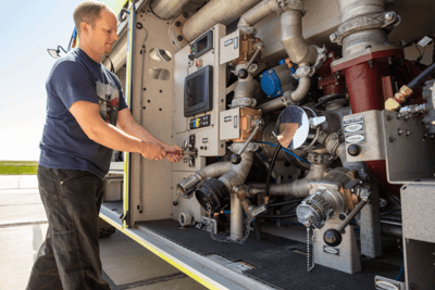 A man in a short sleeved shirt works on an ARFF vehicle.