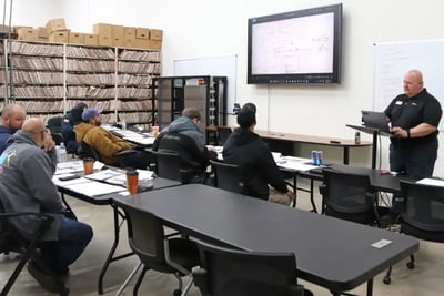 An instructor presents a schematic to technicians during an ARFF technical training classroom session.
