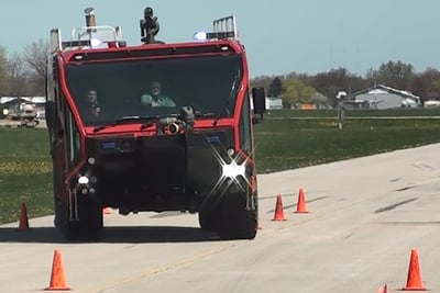 The Oshkosh Striker ARFF undergoing the NATO Lane Change Test on a test track with orange safety cones..