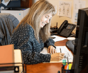 A woman working at a desk with paper and a phone on it.