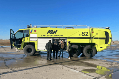 A Striker 6x6 ARFF parked outside with customers performing training on a sunny day.