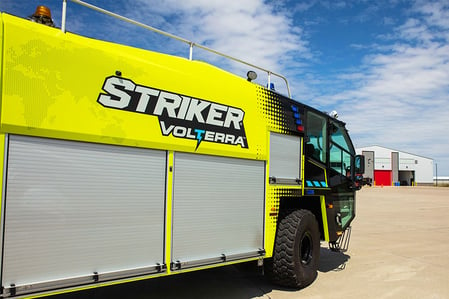 Side of Oshkosh Striker Volterra electric ARFF vehicle with roll-up doors