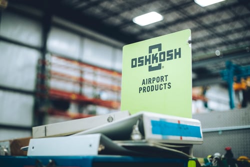 Oshkosh Airport Products logo indoors on a stack of binders.