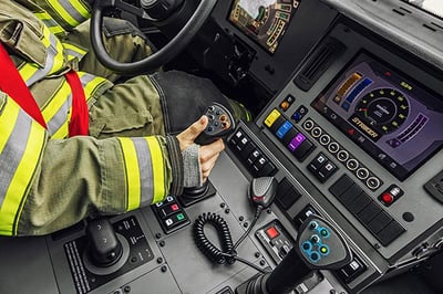 Right hand of firefighter controlling joystick inside Striker ARFF truck.