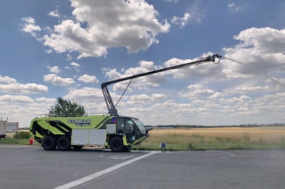 Right side view of Striker Volterra electric ARFF truck with Snozzle turret extended and spraying water.