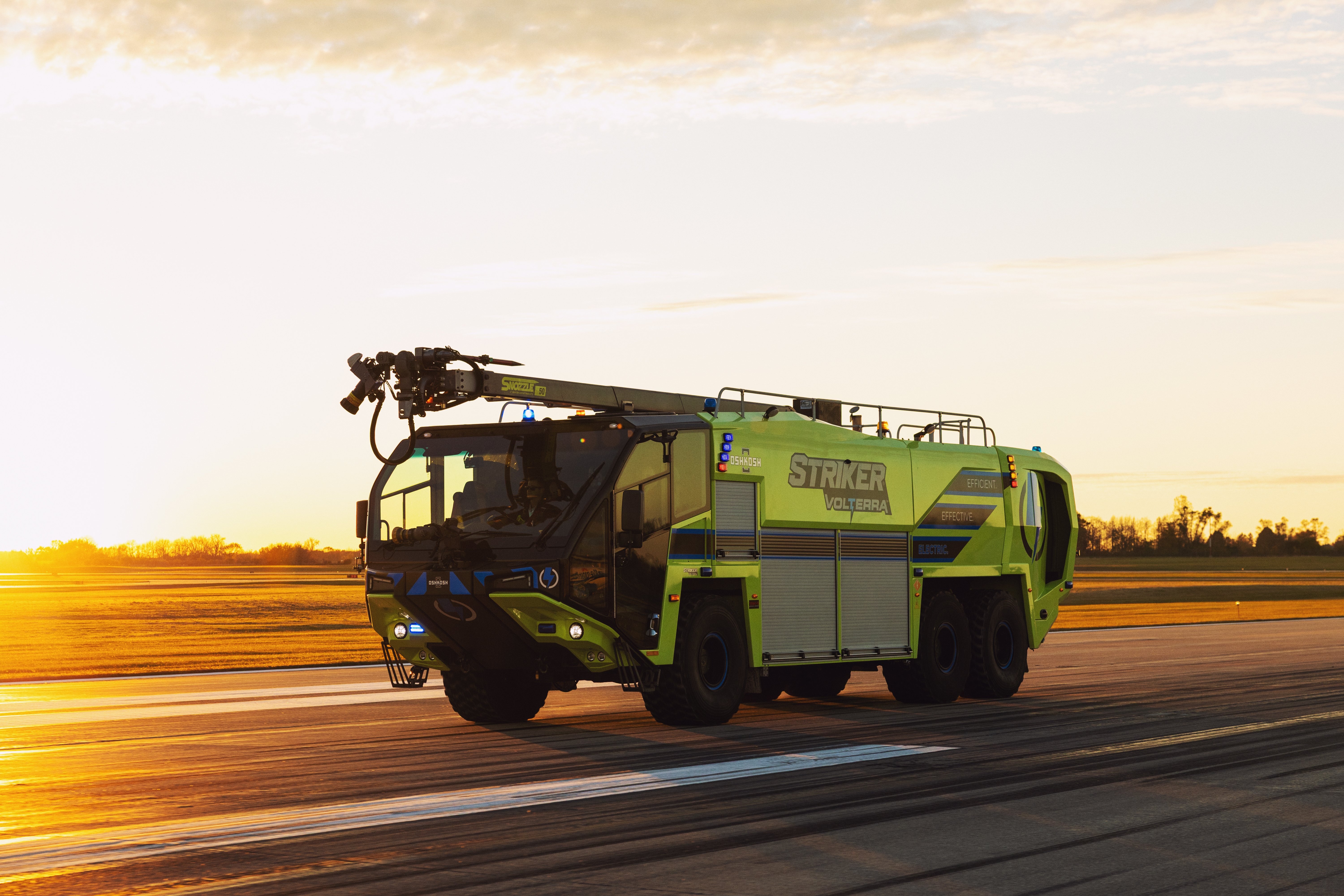 A Striker Volterra Electric ARFF driving down the runway at sunset.