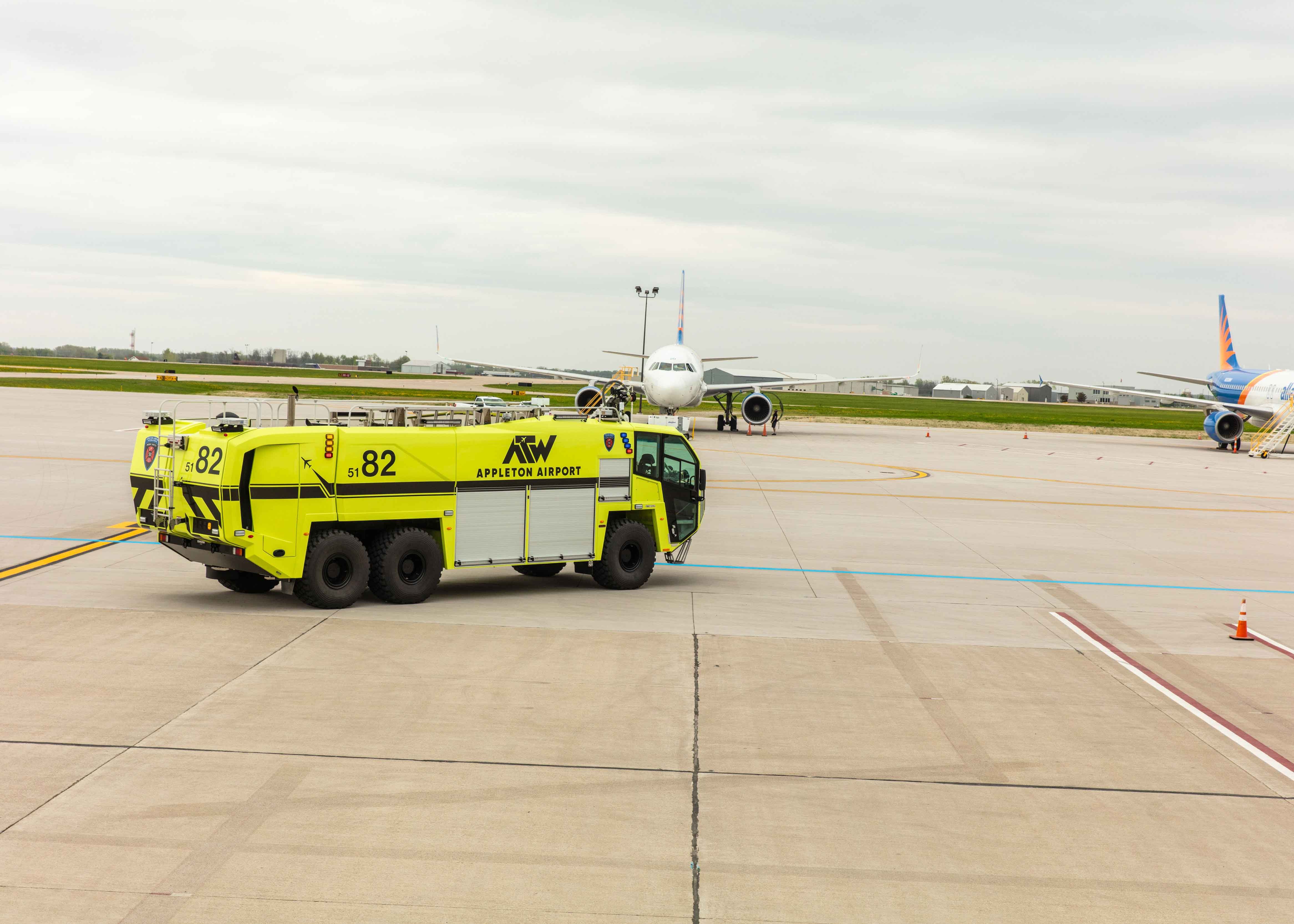 A Striker 6x6 ARFF driving outside at Appleton International Airport on a cloudy day.