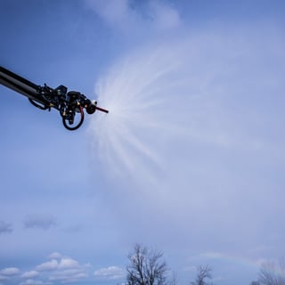 Water being sprayed from a Striker ARFF vehicle Snozzle high reach extendable turret outside on a cloudy day.