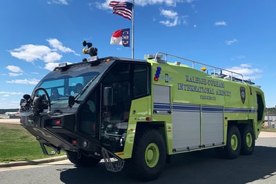 A neon green third generation Striker ARFF truck on the road with a blue sky in the background