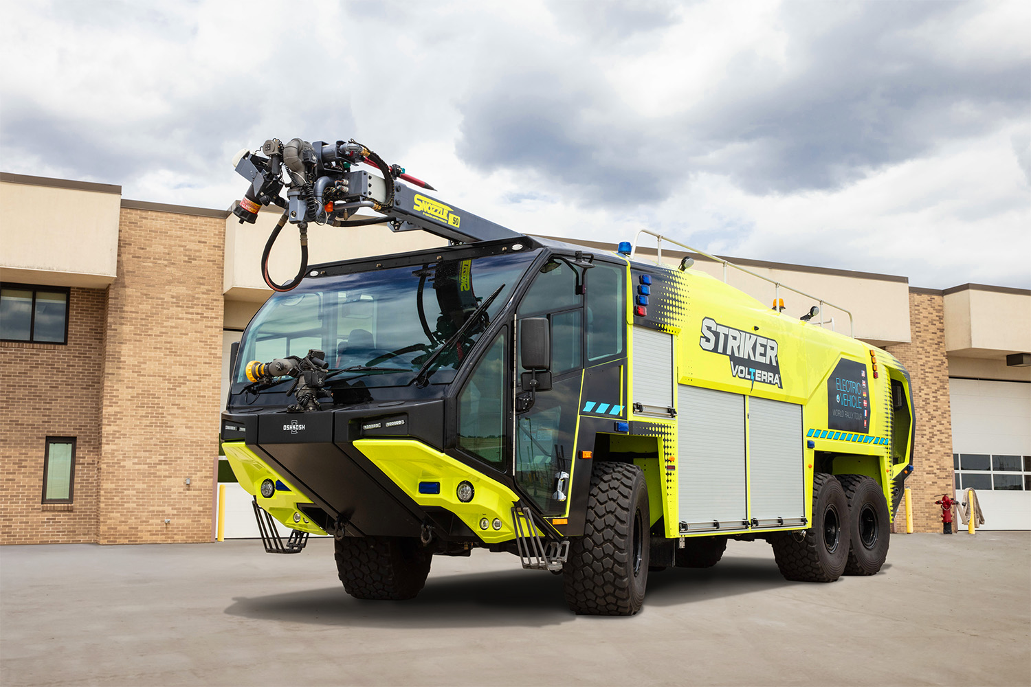 Striker Volterra electric ARFF with a Snozzle parked outside on a cloudy day in front of an airport fire station.