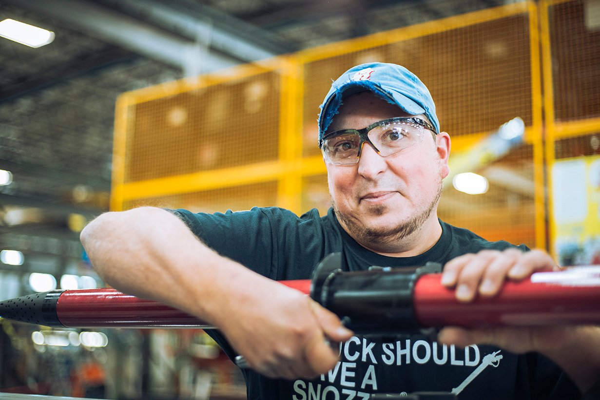 Male Oshkosh Airport Products employee working on a part of a Striker ARFF vehicle.