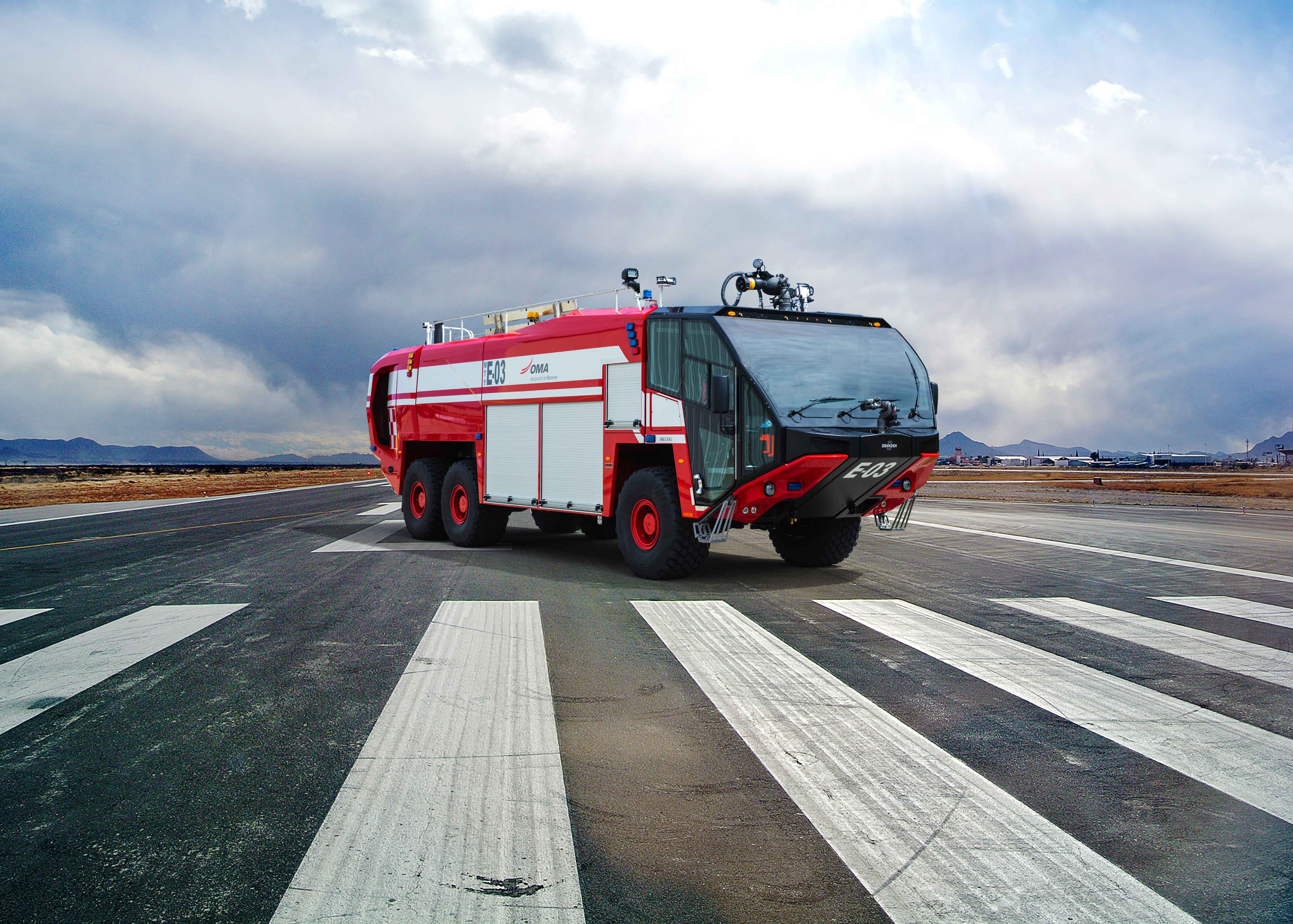 A Striker 6x6 ARFF for Monterrey International Airport parked outside on a runway on a cloudy day.
