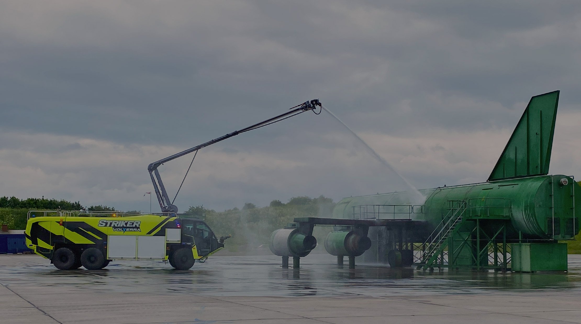 Oshkosh Striker Volterra electric ARFF vehicle with the Snozzle high reach extendable turret extended spraying water.