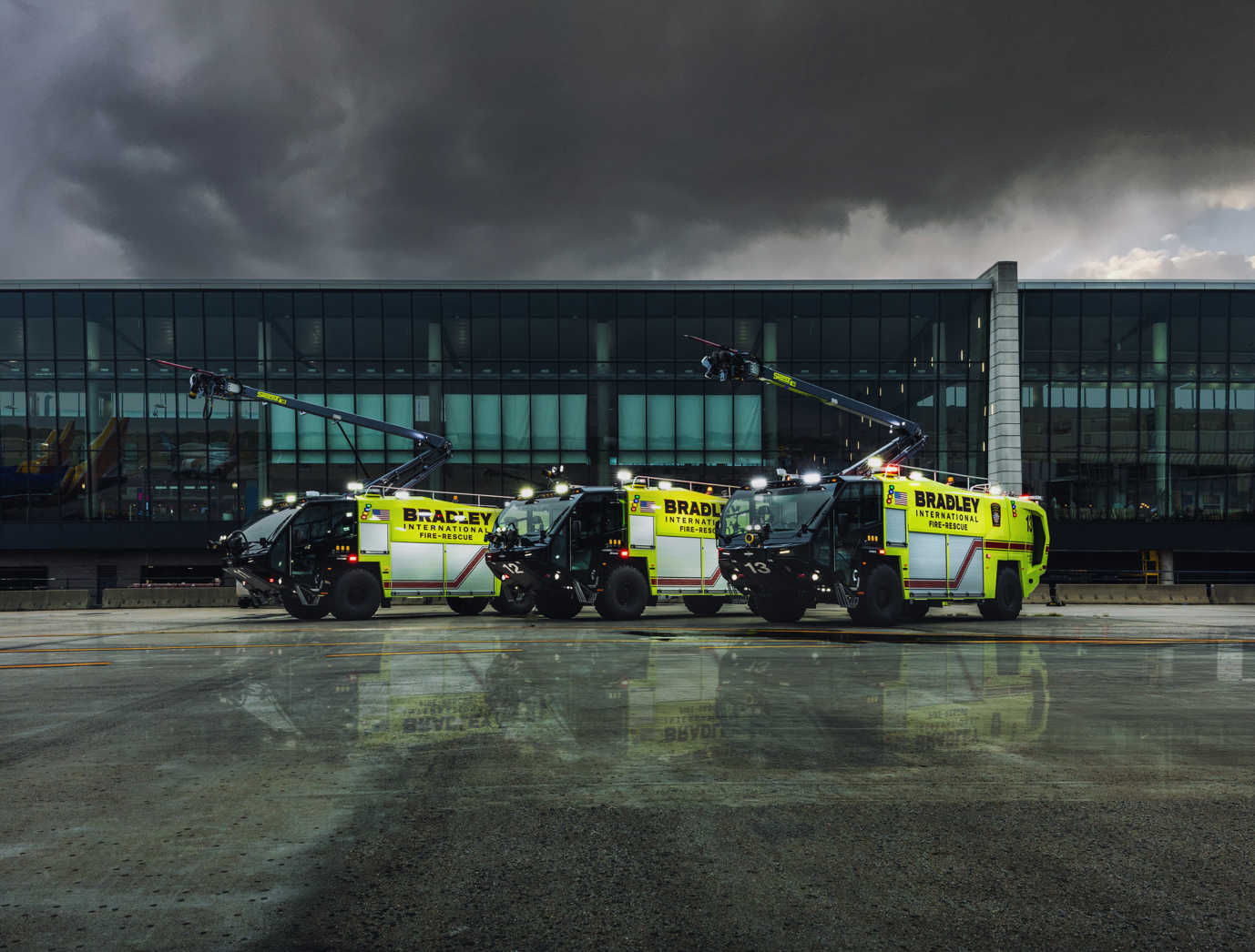 Three Striker 4x4 ARFFs parked outside on a stormy night.