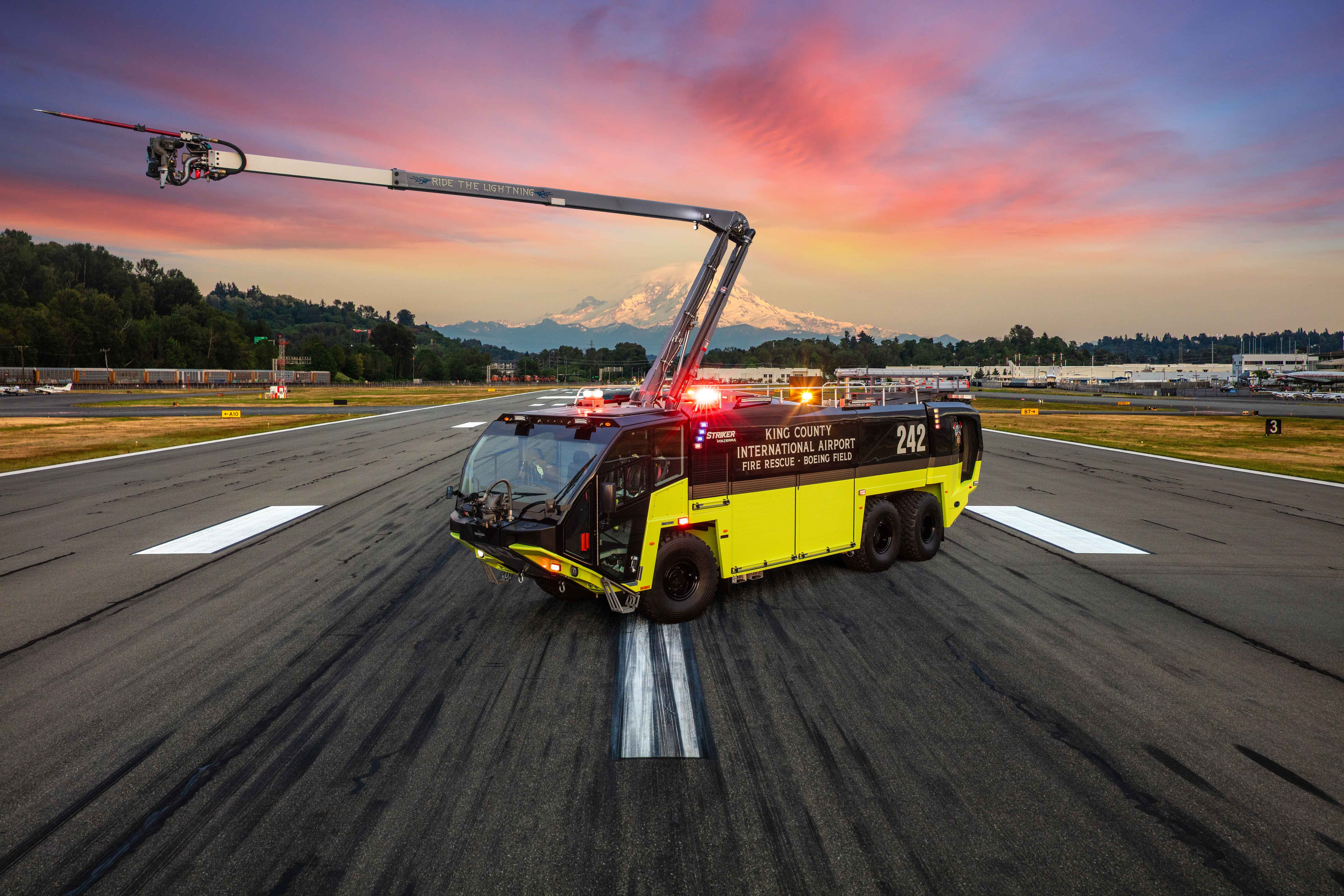 A Striker Volterra electric ARFF for King County International Airport parked outside on the runway at sunset.