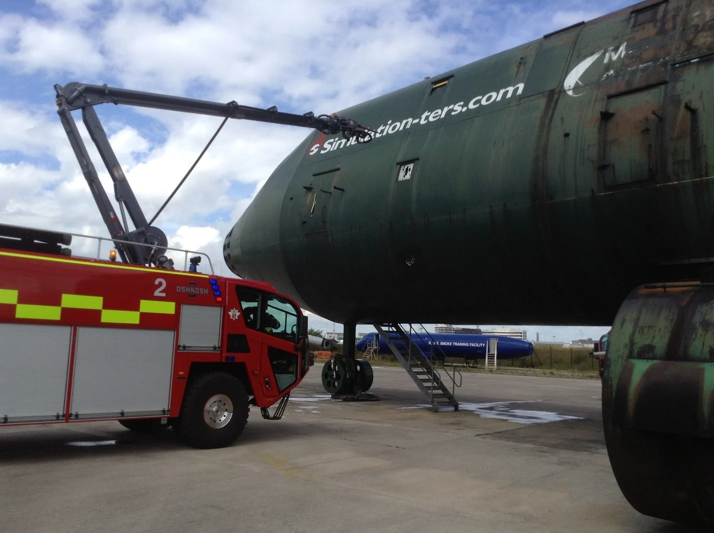 ARFF Truck with a Snozzle piercing a large airplane.